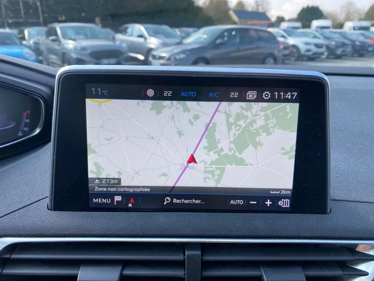 Écran central du tableau de bord du Peugeot 3008 blanc, affichant la navigation GPS en extérieur.