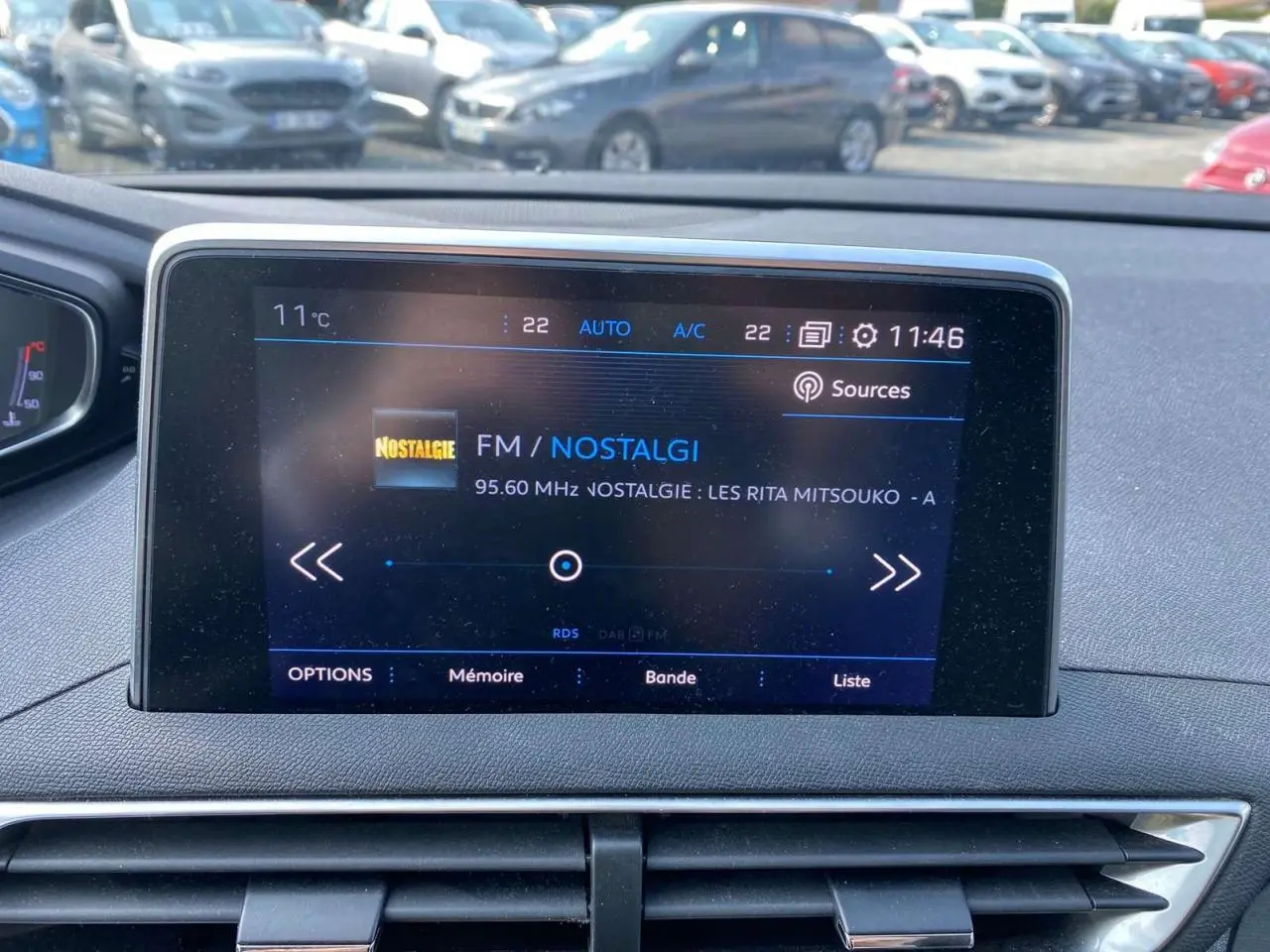 Écran central tactile du Peugeot 3008 blanc, affichant la radio FM Nostalgie, vue intérieure frontale.
