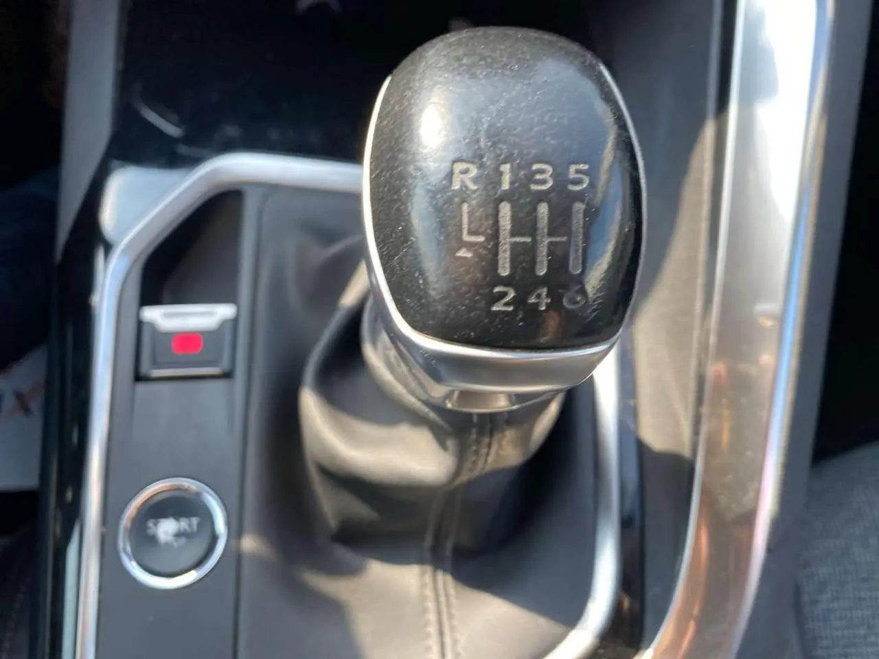 Gros plan sur le levier de vitesses manuelle noir du Peugeot 3008 blanc, avec bouton mode Sport visible à gauche.