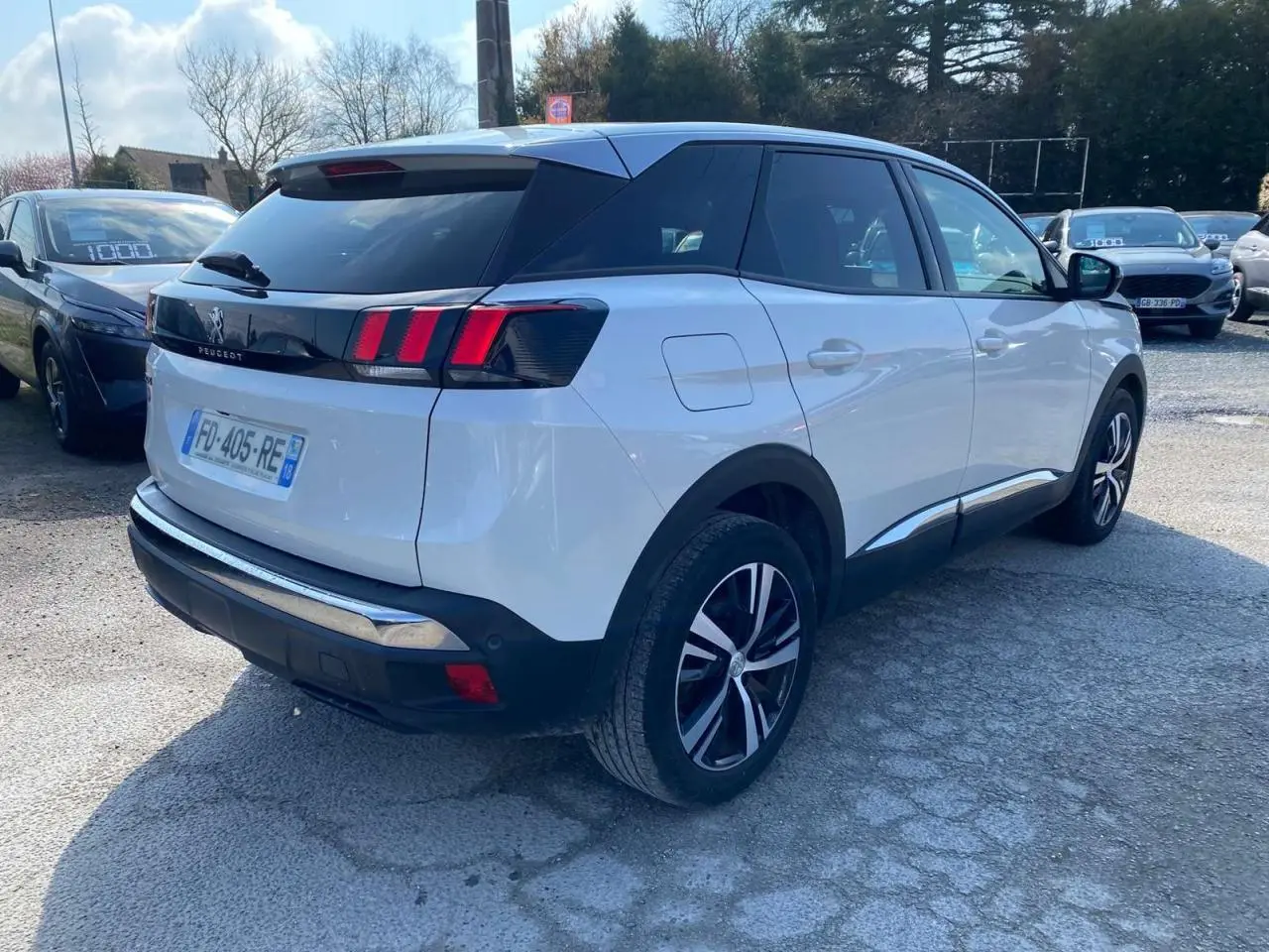 Vue 3/4 arrière droite d'un Peugeot 3008 blanc avec feux arrière à trois griffes et vitres surteintées.