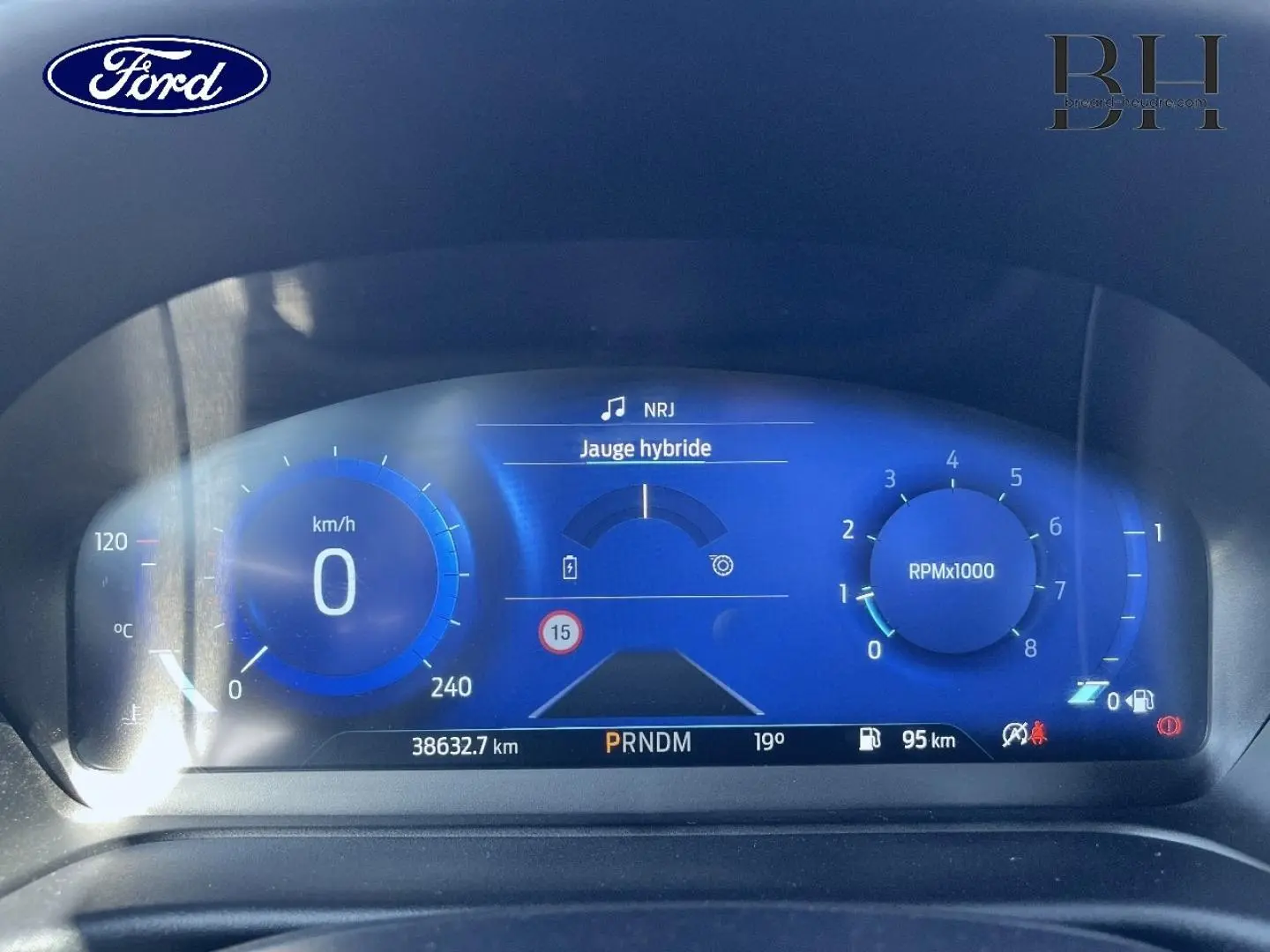Tableau de bord numérique bleu du Ford Puma 2022, affichant vitesse, jauge hybride et compte-tours RPM.