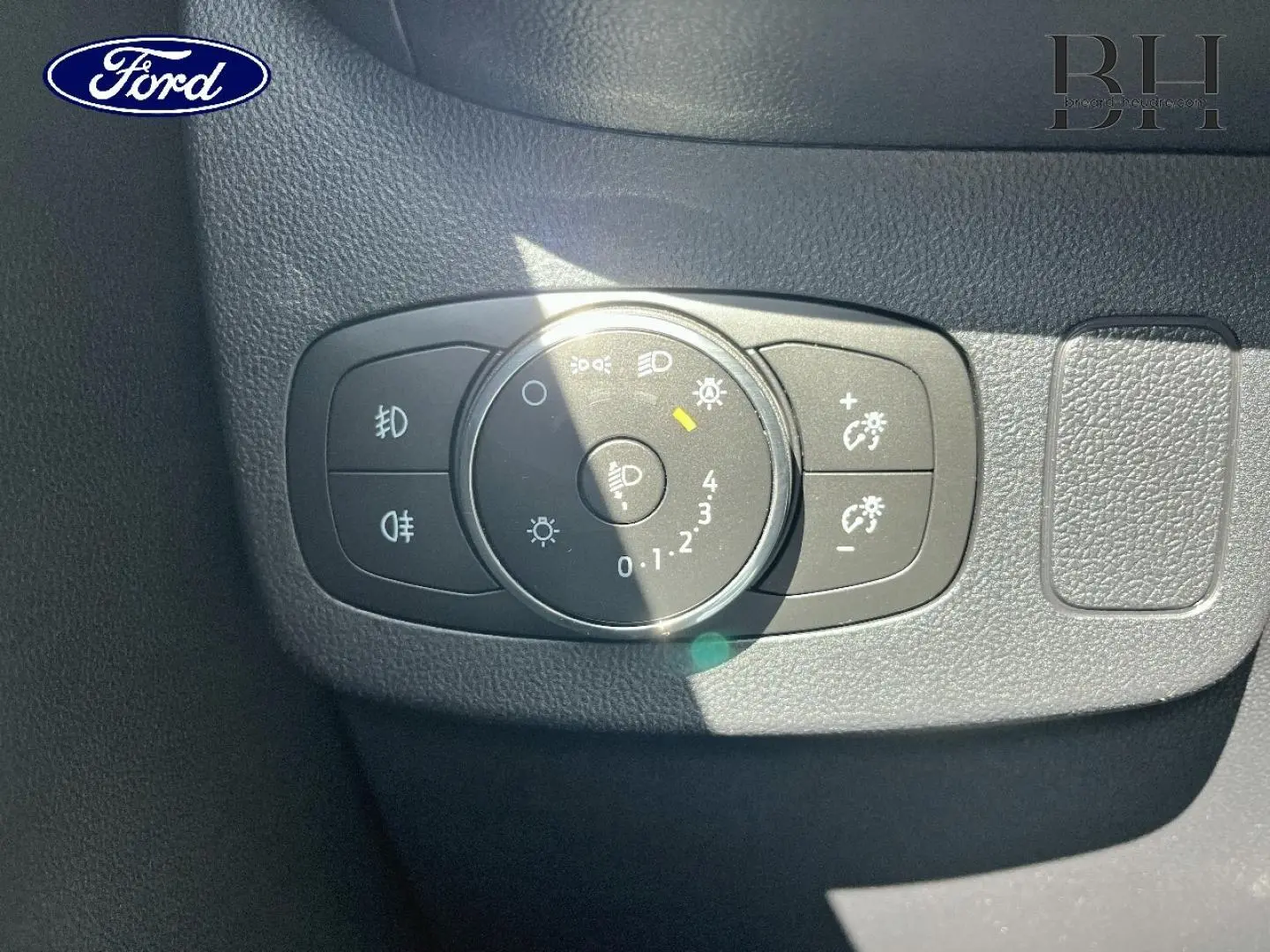Gros plan sur la molette de réglage des phares du tableau de bord d’un Ford Puma gris Solar Métallisé.