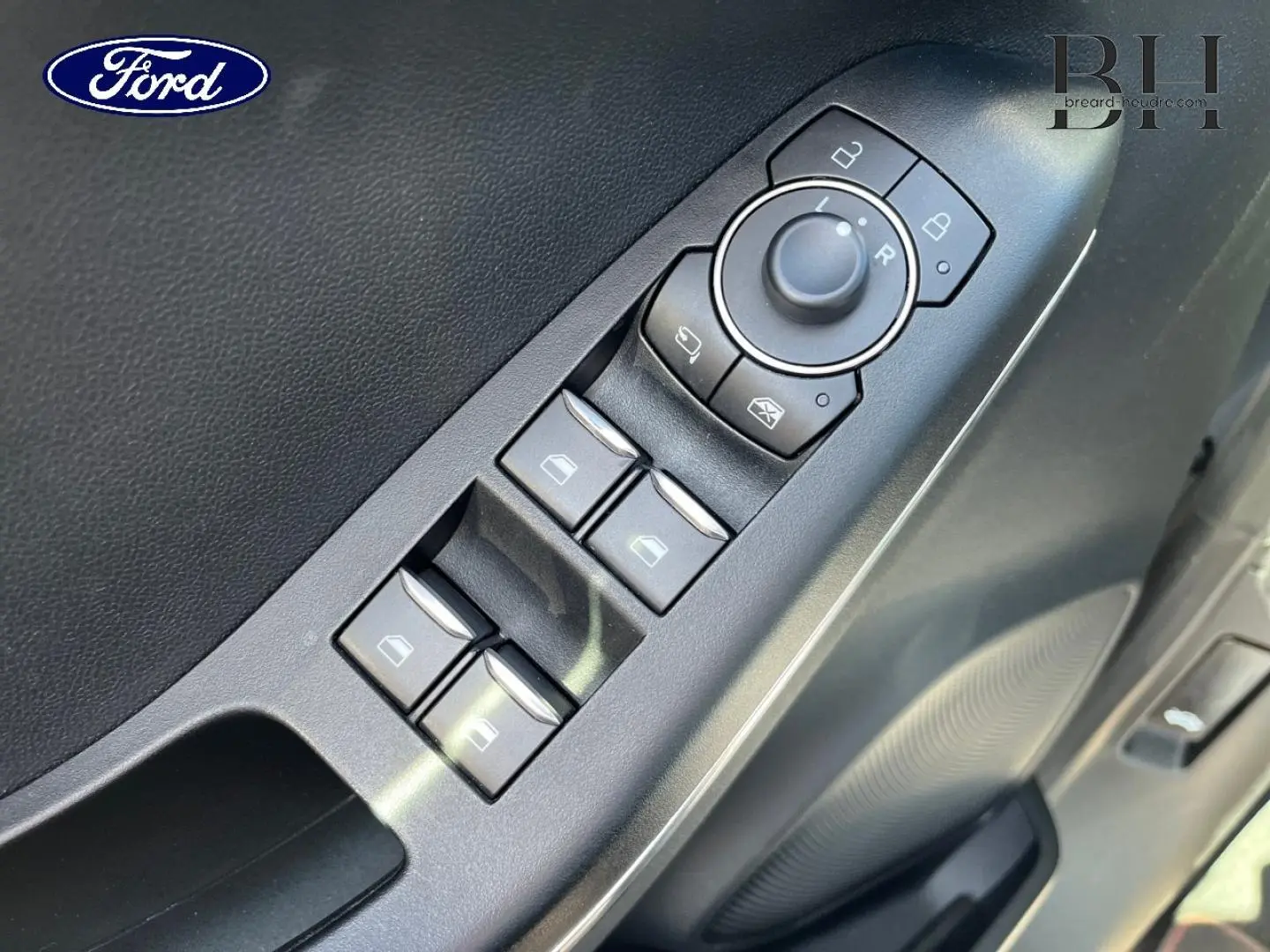 Gros plan sur les commandes des vitres et rétroviseurs côté conducteur d'une Ford Puma 2022 gris Solar métallisé.