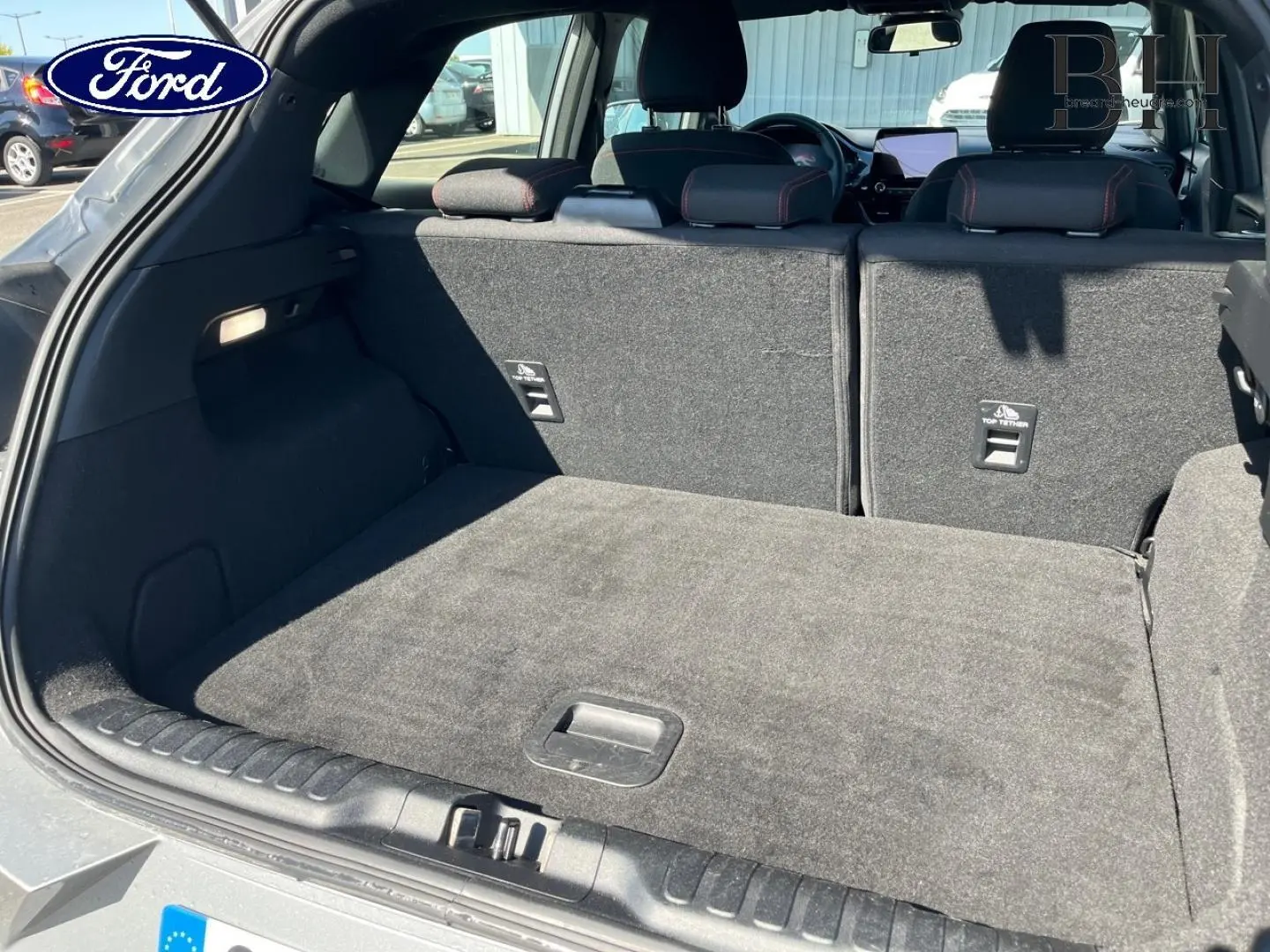 Coffre ouvert du Ford Puma gris Solar métallisé, vue arrière montrant la banquette arrière et le plancher de coffre plat.