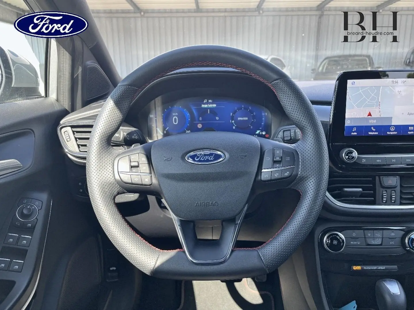 Vue intérieure centrée sur le volant sport perforé avec surpiqûres rouges du Ford Puma 2022, écran tactile et tableau de bord numérique.