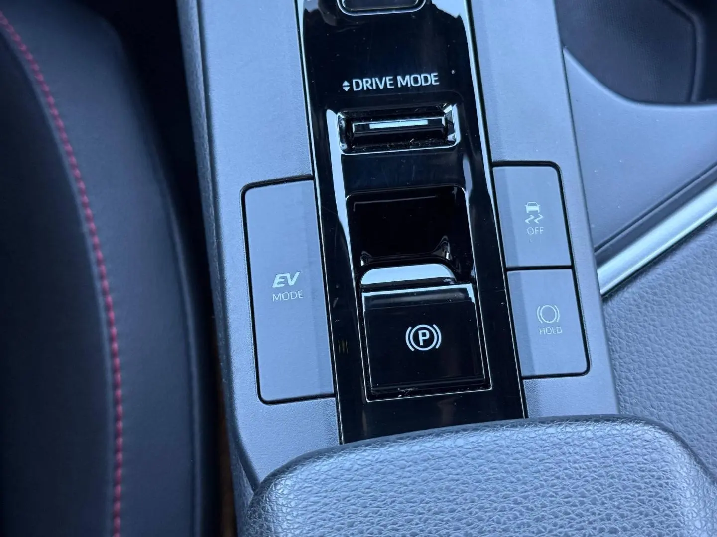 Gros plan sur la console centrale du Toyota C-HR 2025, boutons EV Mode, Drive Mode et frein à main électronique.