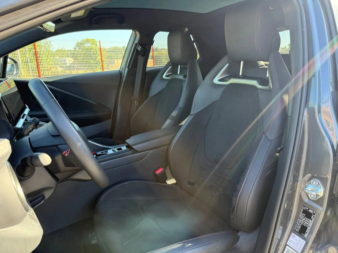 Vue intérieure côté conducteur du Toyota C-HR 2.0 Hybride GR Sport 2025 avec sièges sport noirs et surpiqûres rouges.