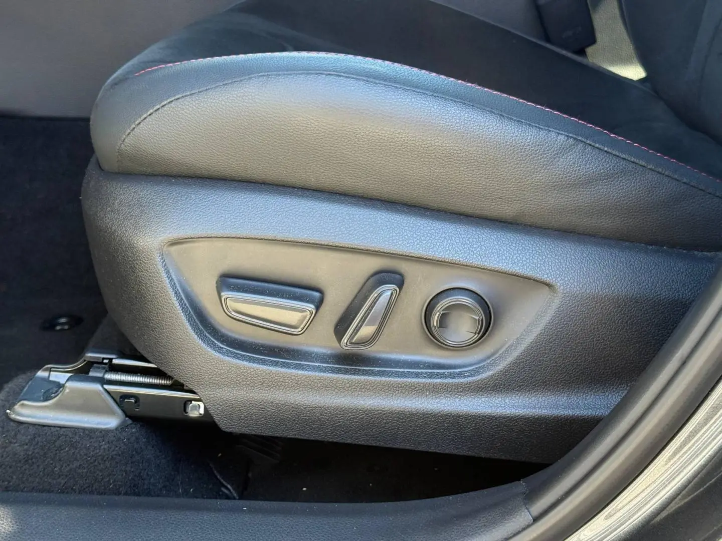 Gros plan sur les commandes électriques du siège conducteur en cuir noir avec surpiqûres rouges du Toyota C-HR GR Sport 2025.