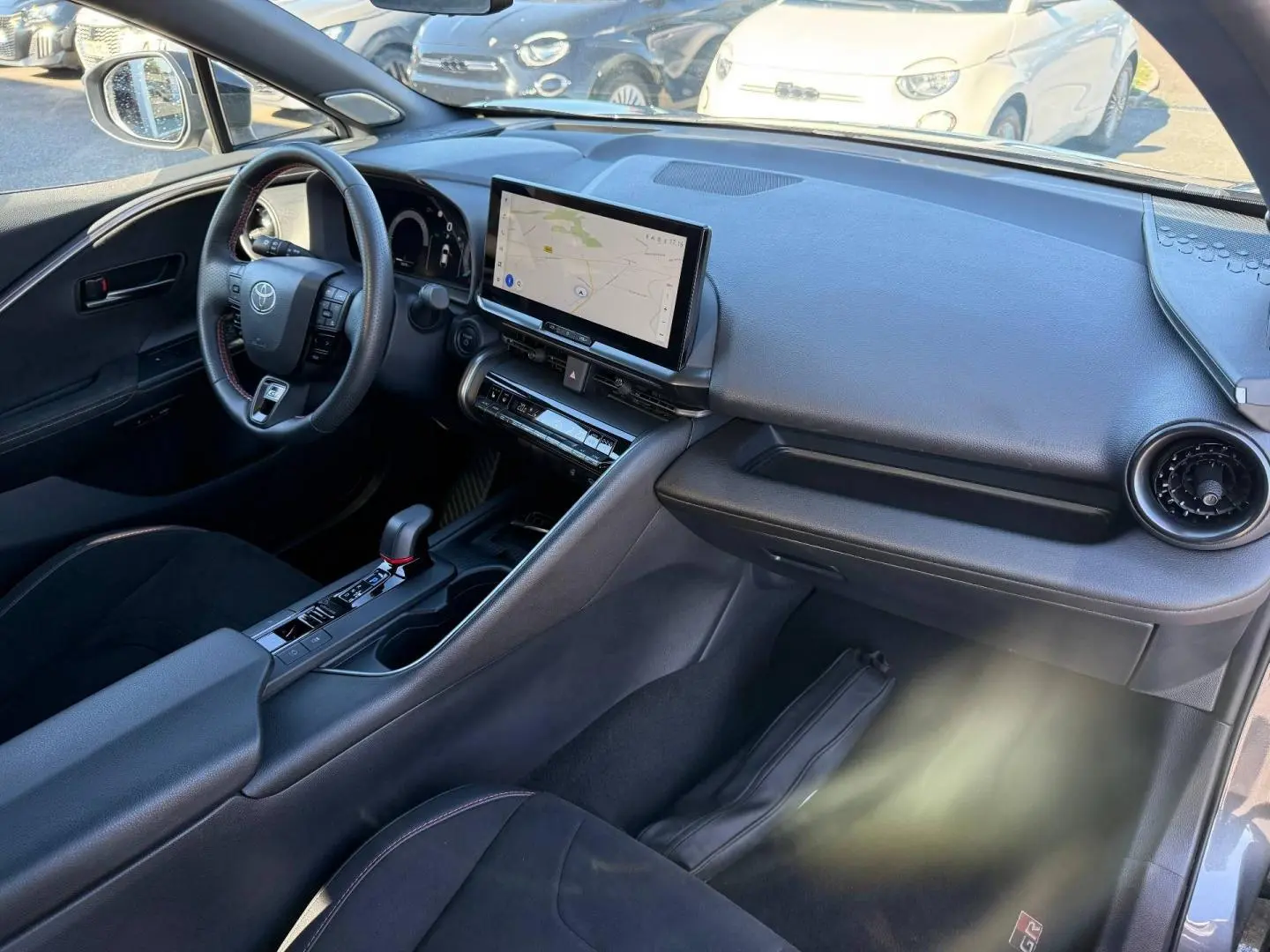 Vue intérieure côté conducteur du Toyota C-HR 2.0 Hybride 200ch GR Sport 2025 avec tableau de bord noir et écran tactile GPS.