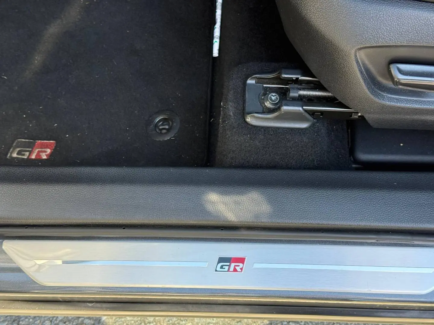 Détail de la plaque de seuil et tapis de sol noirs avec logo GR du Toyota C-HR 2.0 Hybride gris Atlas bi-ton.