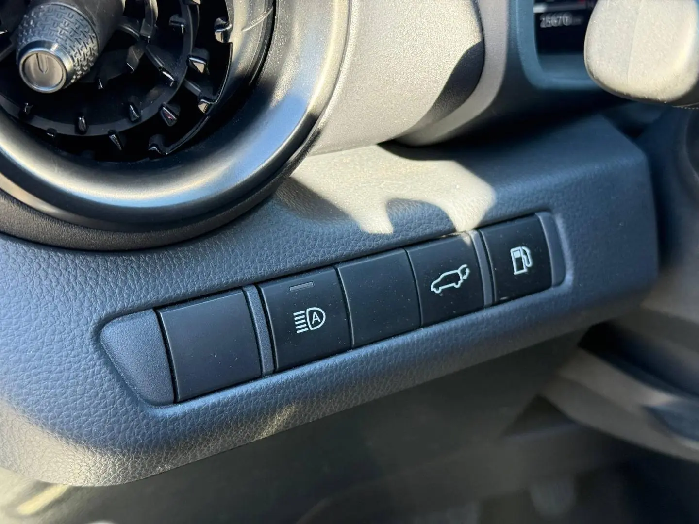 Gros plan sur les boutons de commande noirs à gauche du volant du Toyota C-HR 2.0 Hybride gris Atlas métallisé.