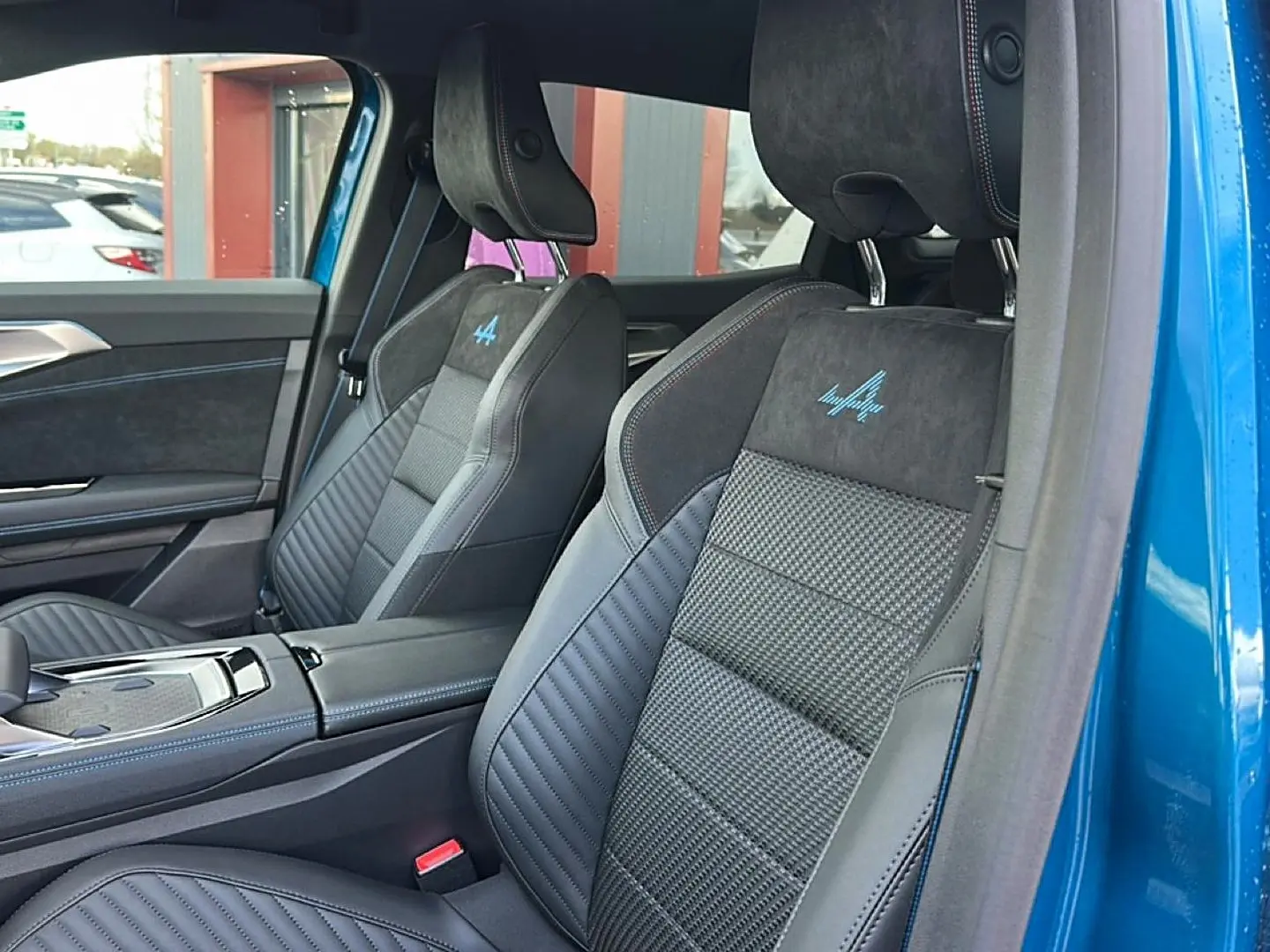 Vue intérieure côté gauche des sièges avant en cuir et alcantara avec logo Alpine bleu sur Renault Austral bleu outremer 2026.