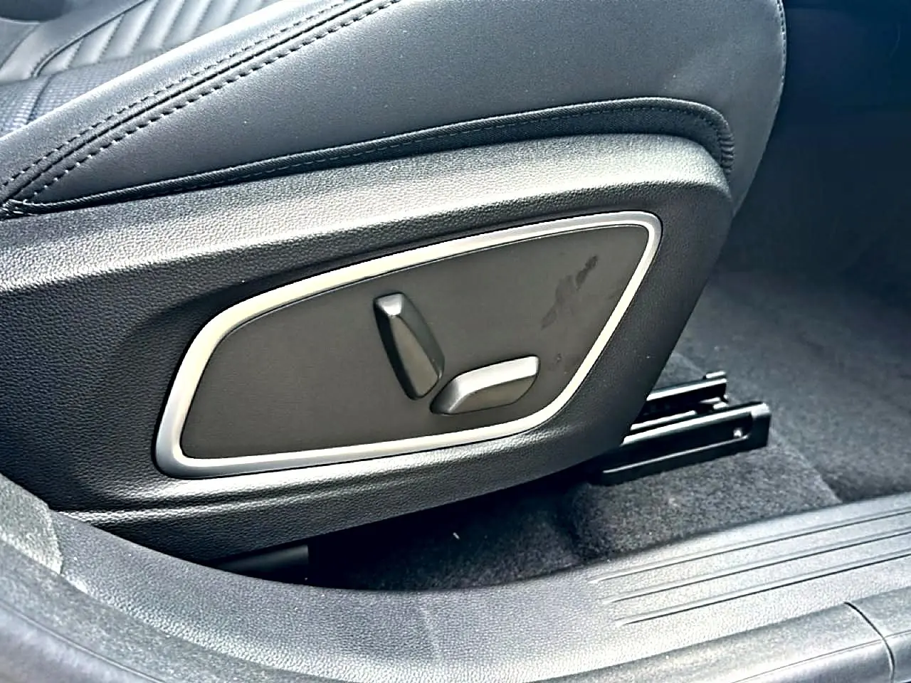 Gros plan sur les commandes électriques du siège conducteur noir du Renault Austral 2026 version hybride.