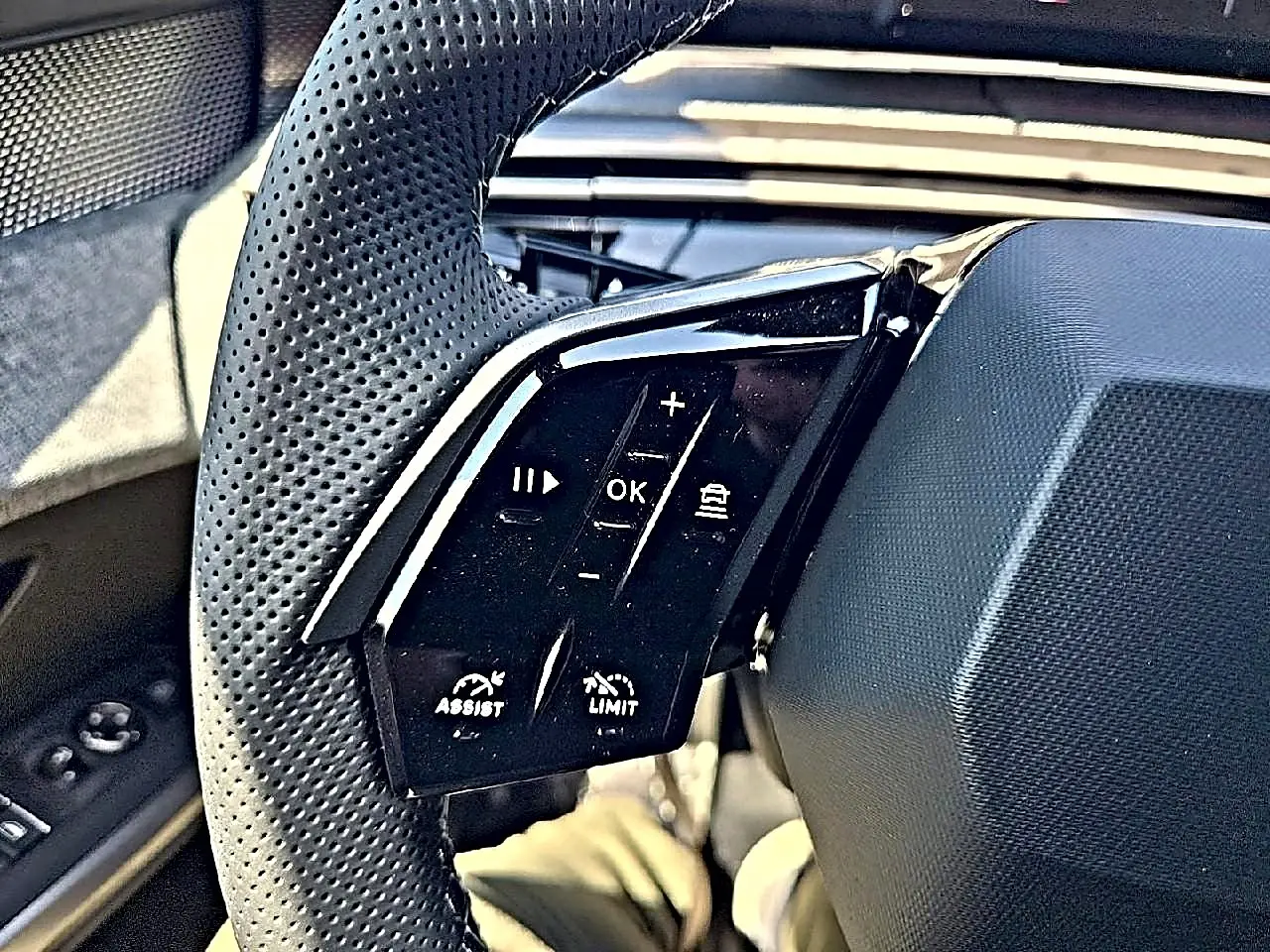 Gros plan sur les commandes gauche du volant cuir perforé du Peugeot 3008 noir, boutons multifonctions visibles.