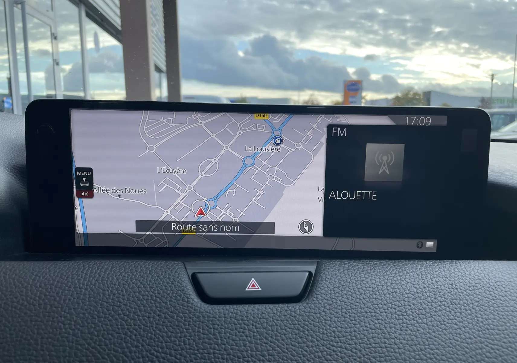 Écran central du tableau de bord du Mazda CX-60 2023 affichant la navigation et la radio FM, vue intérieure frontale.