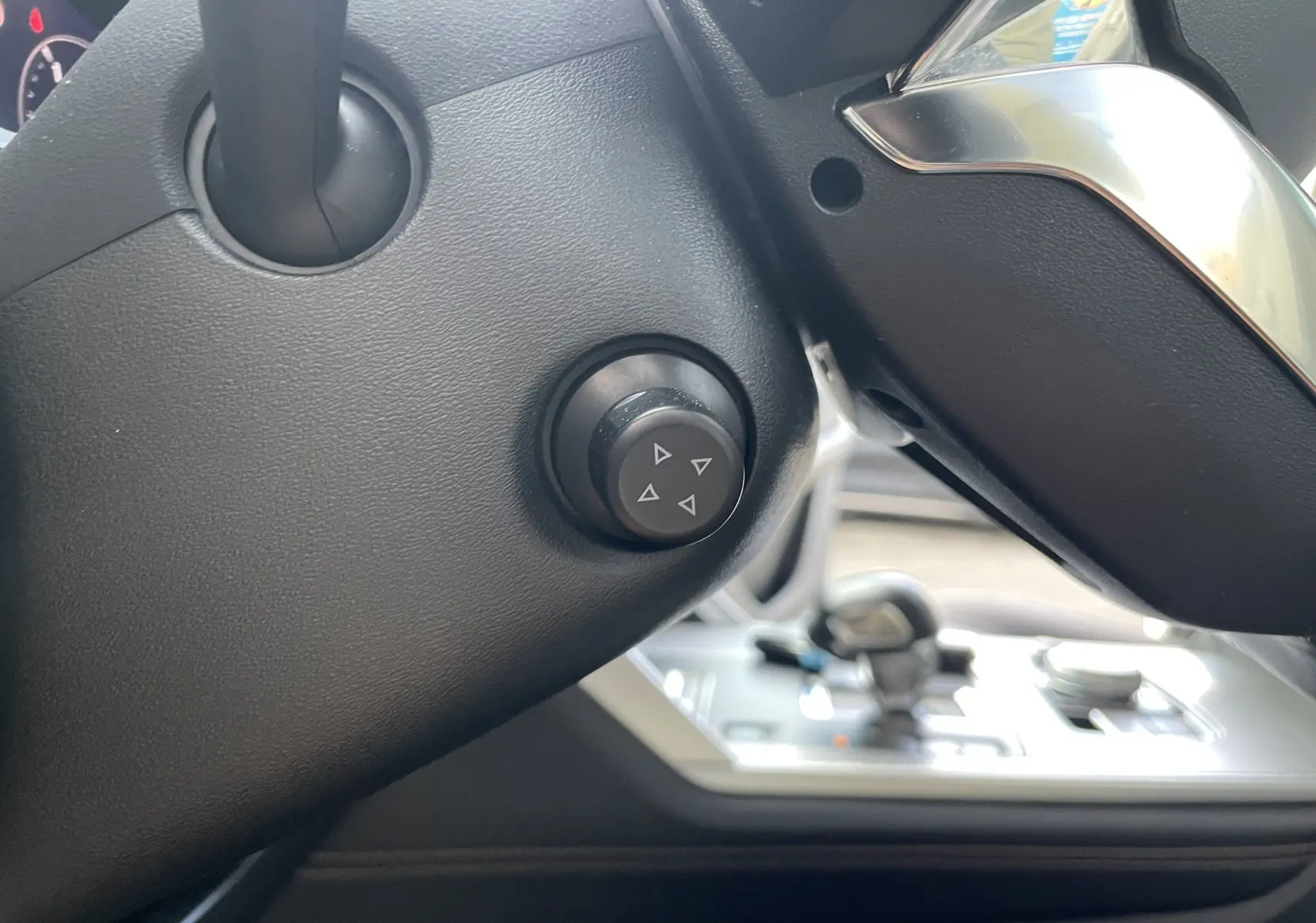 Détail du bouton de réglage sur la colonne de direction noire du Mazda CX-60 2023, intérieur gris-noir.