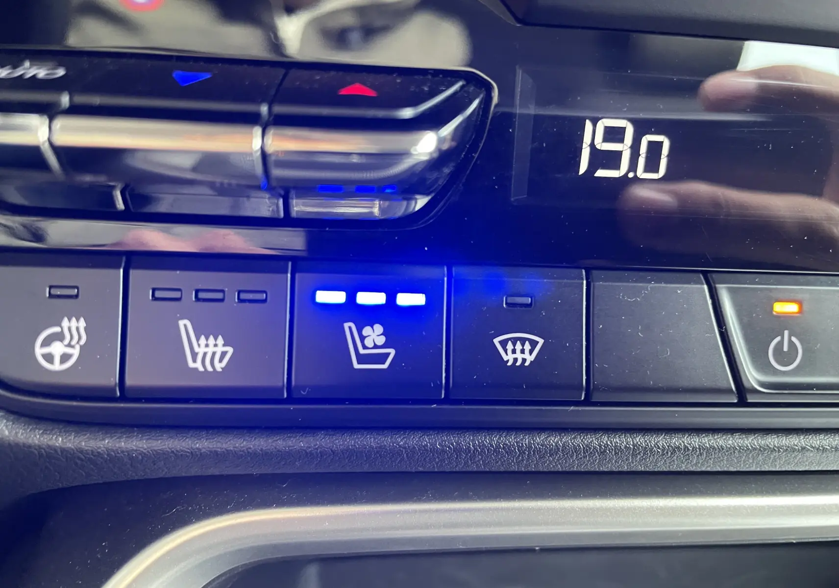 Gros plan sur les commandes de climatisation et sièges ventilés du Mazda CX-60 2023, affichage digital à 19°C.