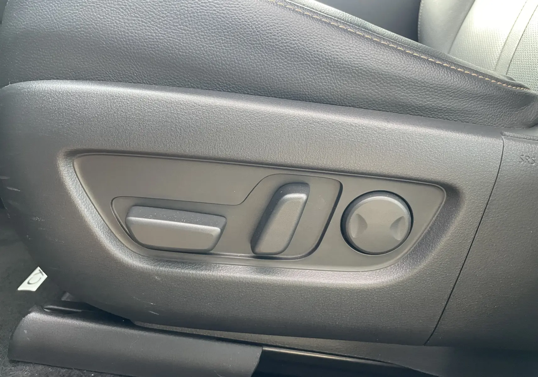 Détail des commandes de réglage électrique du siège avant en cuir noir du Mazda CX-60 blanc nacré 2023.