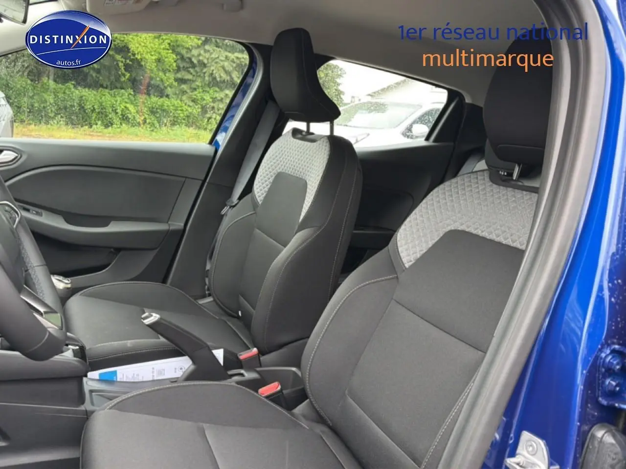 Vue intérieure côté droit de la Renault Clio V bleu iron, montrant les sièges avant en tissu bi-ton gris et noir.