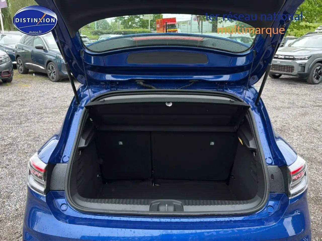 Coffre ouvert vu de l'arrière d'une Renault Clio V bleu iron, montrant l'espace de chargement vide.