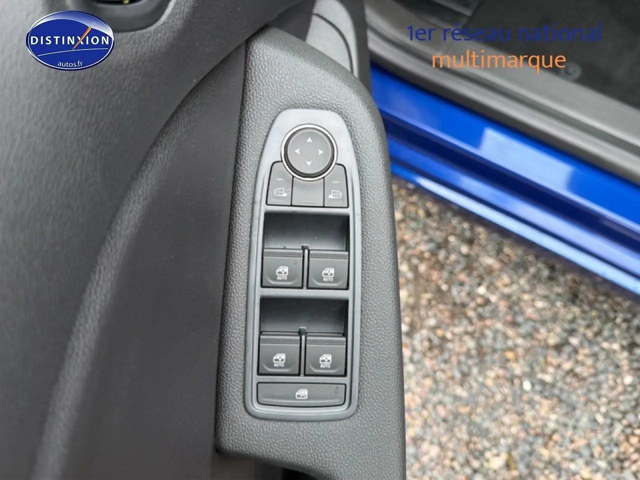 Vue rapprochée des commandes des vitres électriques sur la porte côté gauche d’une Renault Clio V Bleu Iron.