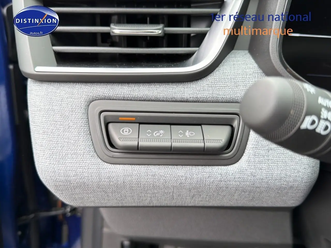 Détail des commandes de réglage des feux et verrouillage sur tableau de bord gris clair d’une Renault Clio V Bleu iron.