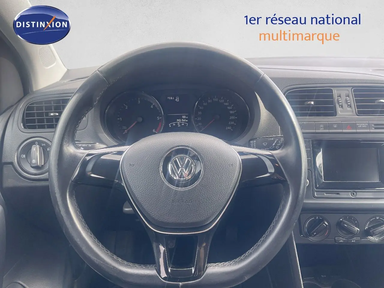 Vue intérieure centrée sur le volant noir d'une Volkswagen Polo 2016 avec tableau de bord et commandes visibles.