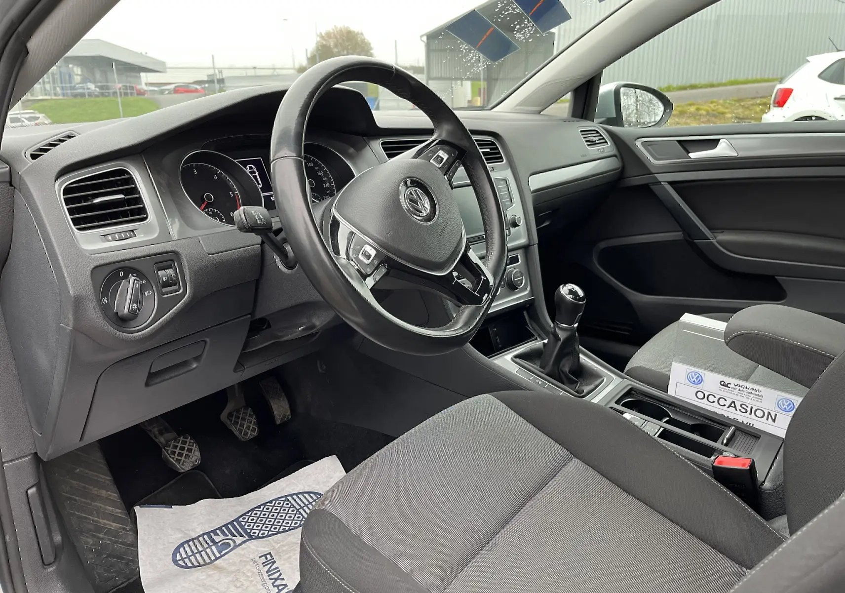 Intérieur noir de Volkswagen Golf 7 2017, vue côté conducteur montrant volant, tableau de bord et levier de vitesses manuel.