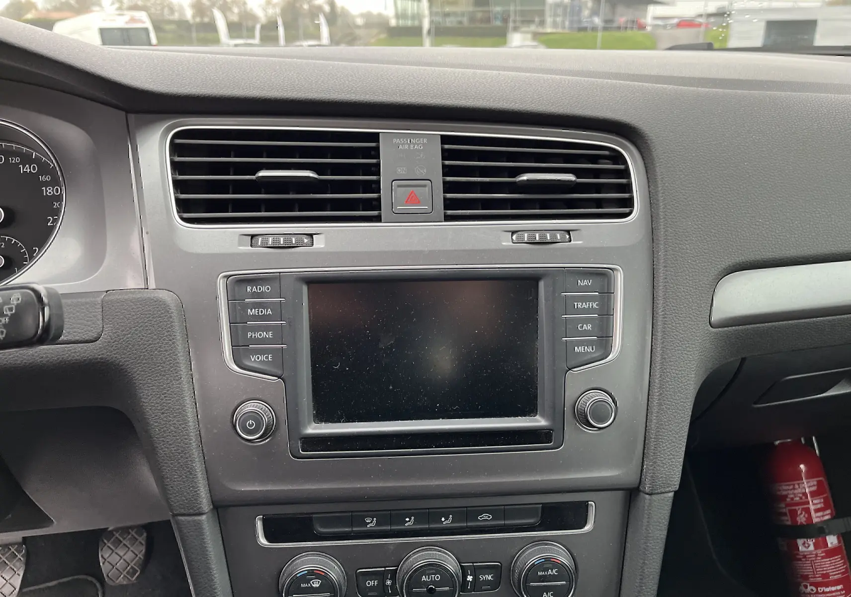 Vue intérieure du tableau de bord noir de la Volkswagen Golf 7 2017 avec écran tactile et commandes de climatisation.