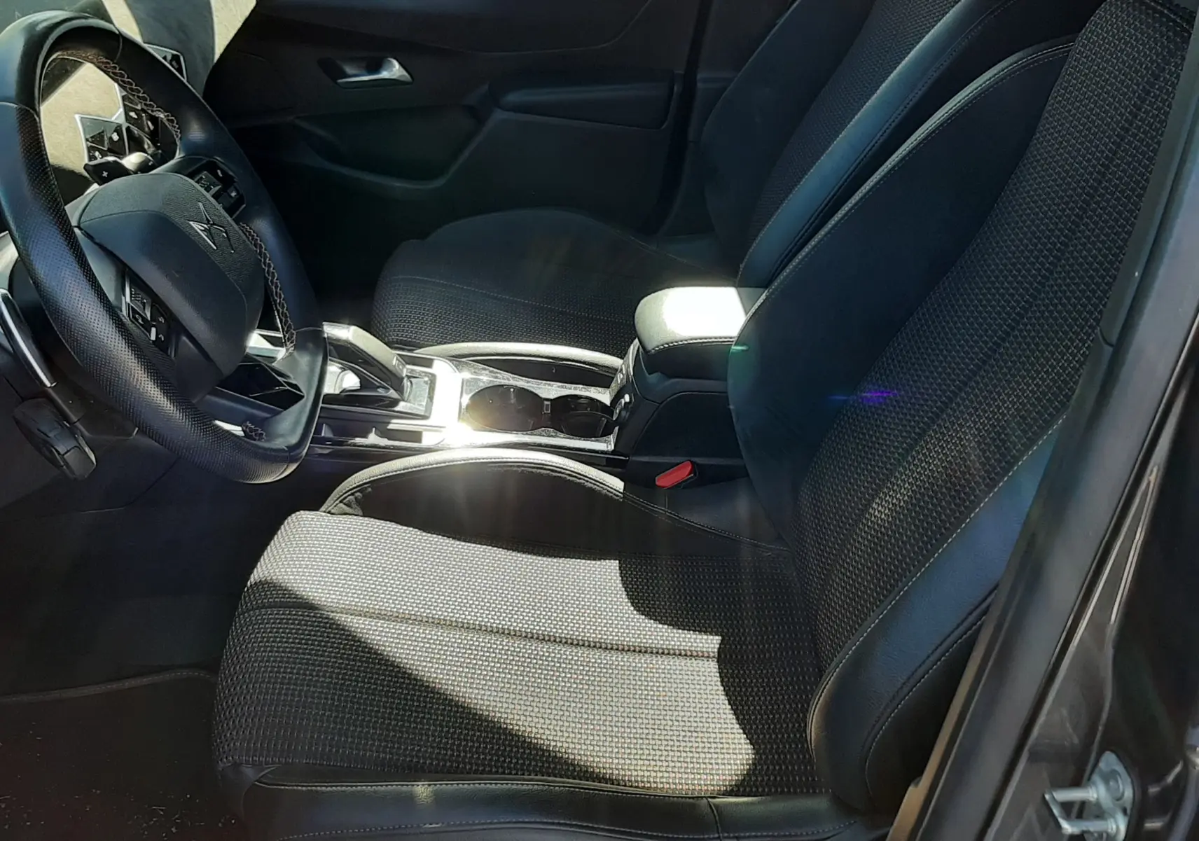 Intérieur avant droit du DS3 Crossback gris foncé 2021, sièges tissu et cuir avec console centrale brillante.