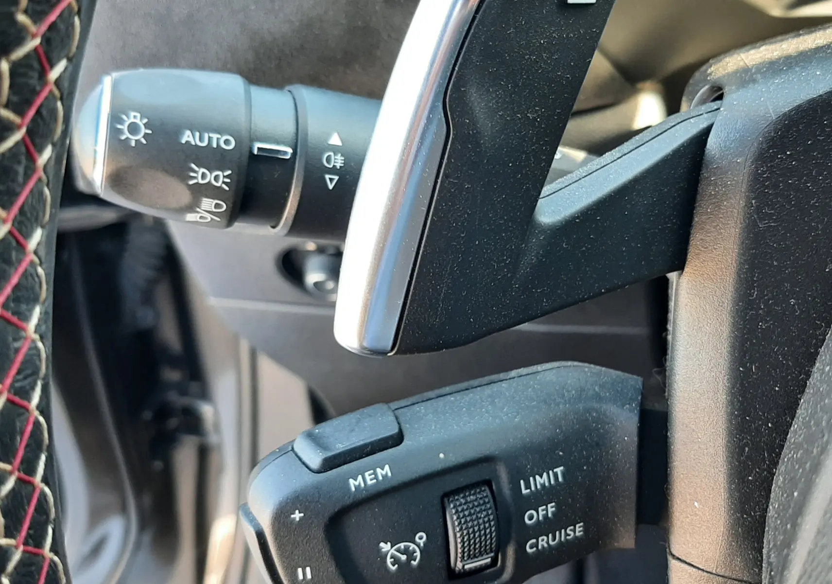 Gros plan sur les commandes au volant du DS3 Crossback gris foncé, montrant les réglages du régulateur de vitesse et les palettes de changement.