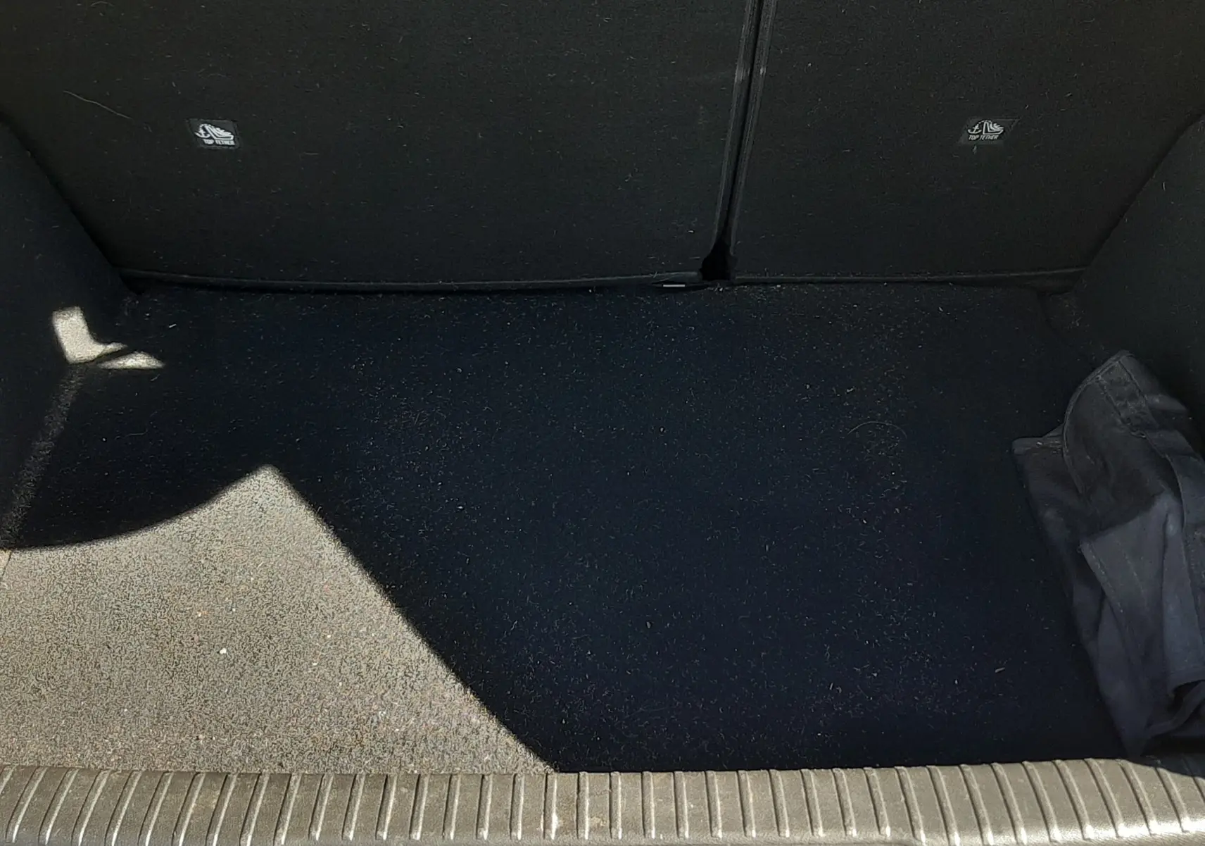 Coffre ouvert vu de face d'un DS3 Crossback gris foncé, montrant un espace de chargement vide avec un tissu noir.