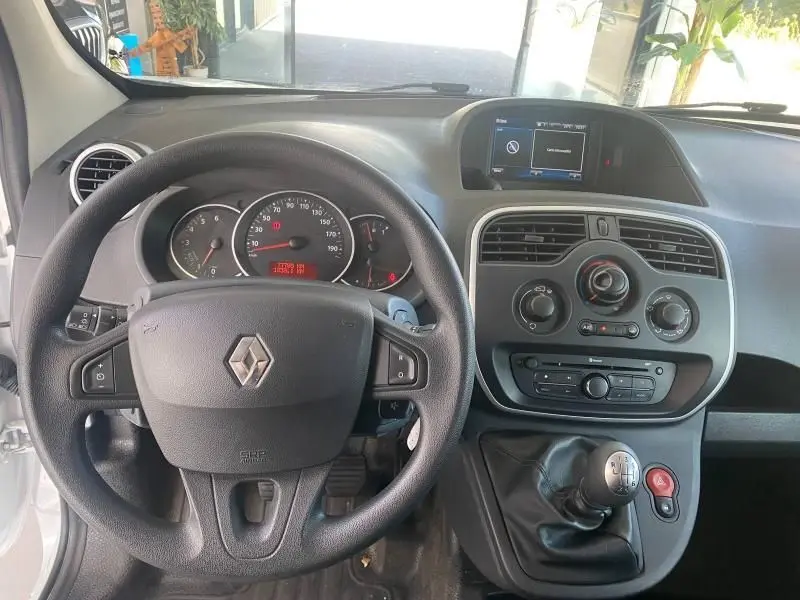 Vue intérieure frontale du tableau de bord et volant noir du Renault Kangoo Express blanc, avec écran tactile et commandes au volant visibles.