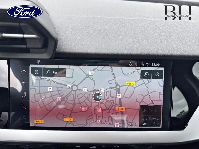 Écran tactile GPS affichant une carte de navigation dans l'habitacle d'une Audi A3 Sportback noire, vue de face.
