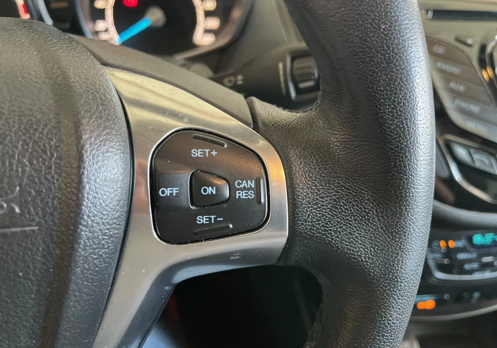 Gros plan sur les commandes de régulateur de vitesse au volant cuir noir d'une Ford B-MAX titanium 2015.