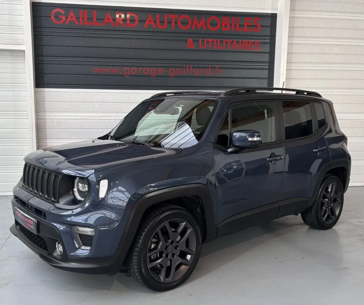 Jeep Renegade bleu vue 3/4 avant droit avec jantes noires et toit noir en intérieur de garage.