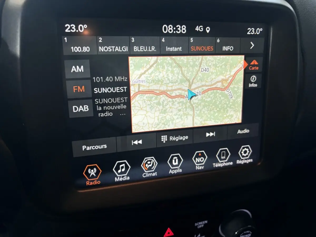 Écran tactile central affichant la navigation et la radio dans l'habitacle d'une Jeep Renegade bleu 2021.