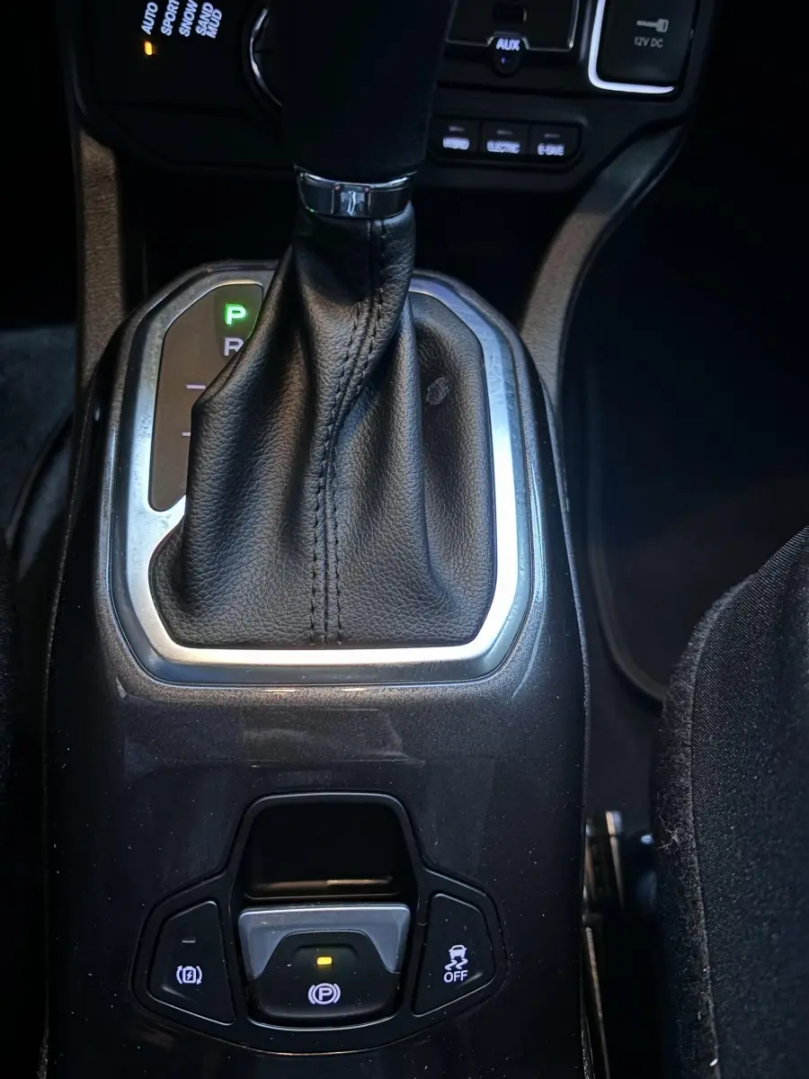 Le levier de vitesses automatique noir et chrome de la Jeep Renegade hybride rechargeable vue de dessus, avec boutons de frein et contrôle de stabilité.