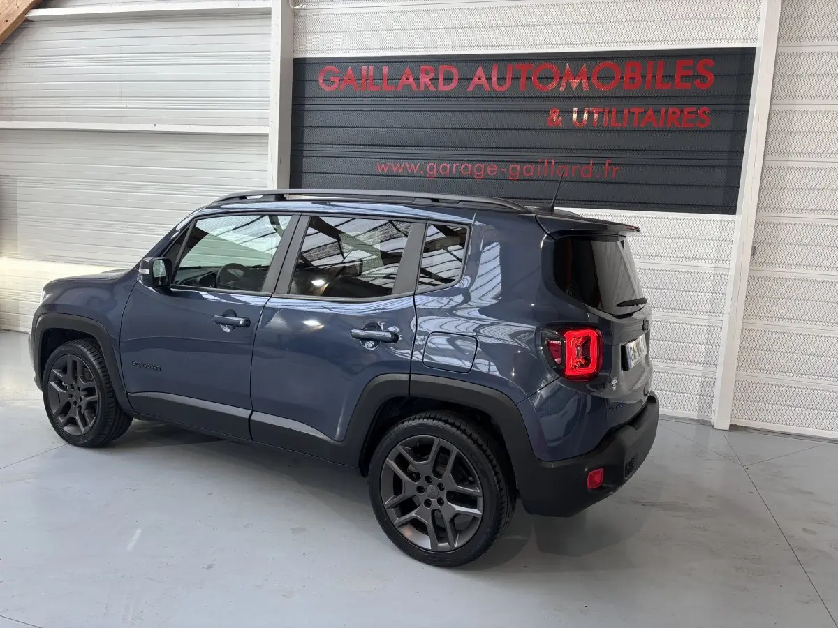 Jeep Renegade bleu vue 3/4 arrière droit dans un garage avec jantes noires et vitres teintées.