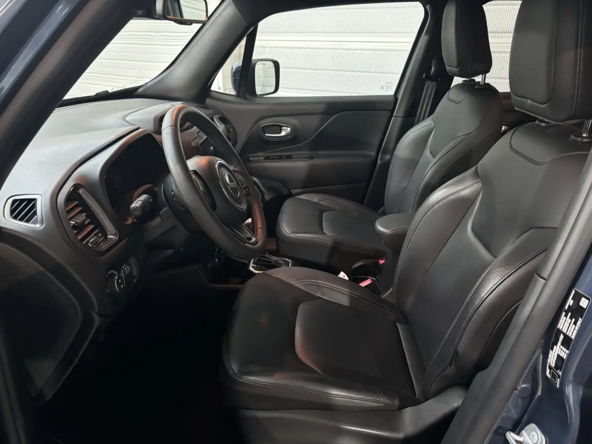 Intérieur avant droit du Jeep Renegade bleu 2021 avec sièges cuir noirs et tableau de bord moderne.