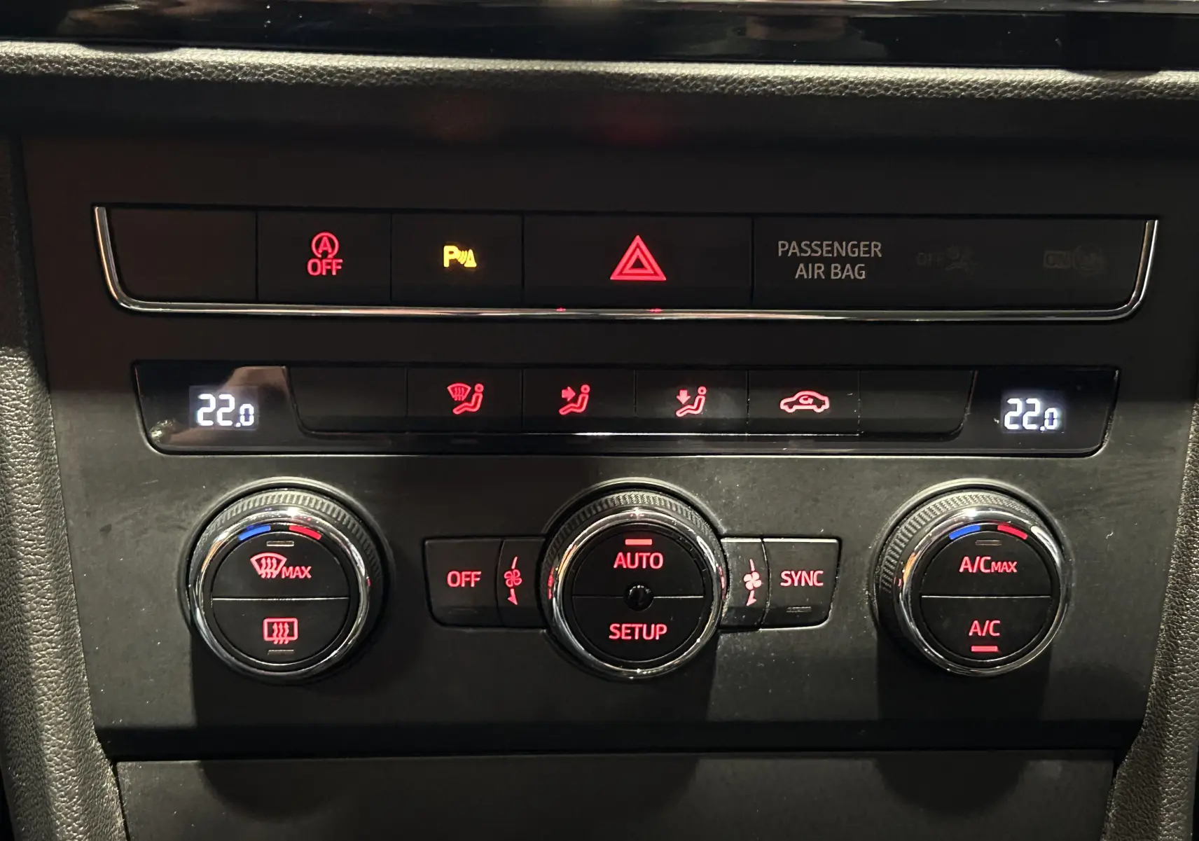 Vue rapprochée de la console centrale noire du SEAT Leon 2014, avec commandes climatisation et alertes lumineuses.