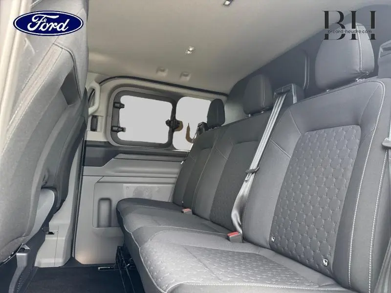Vue intérieure côté droit sur la banquette arrière noire du Ford Transit Custom Fourgon 2026 avec vitres latérales entrebaillantes.