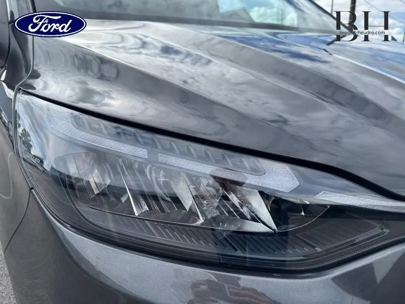 Gros plan sur le phare avant gauche LED du Ford Transit Custom Fourgon gris Magnetic métallisé, montrant les détails du bloc optique.