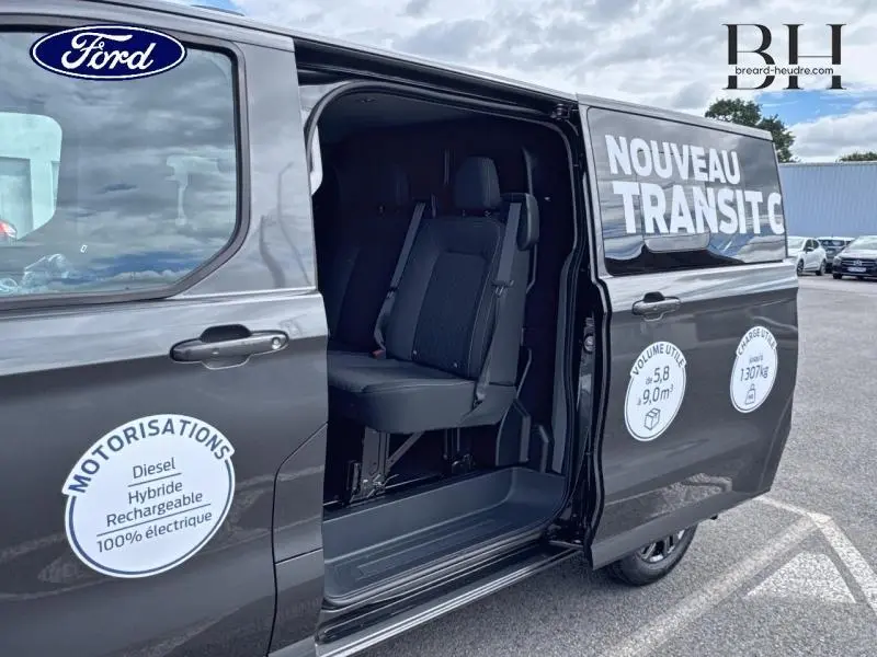Vue latérale droite du Ford Transit Custom gris métallisé avec porte coulissante ouverte et sièges visibles à l'intérieur.