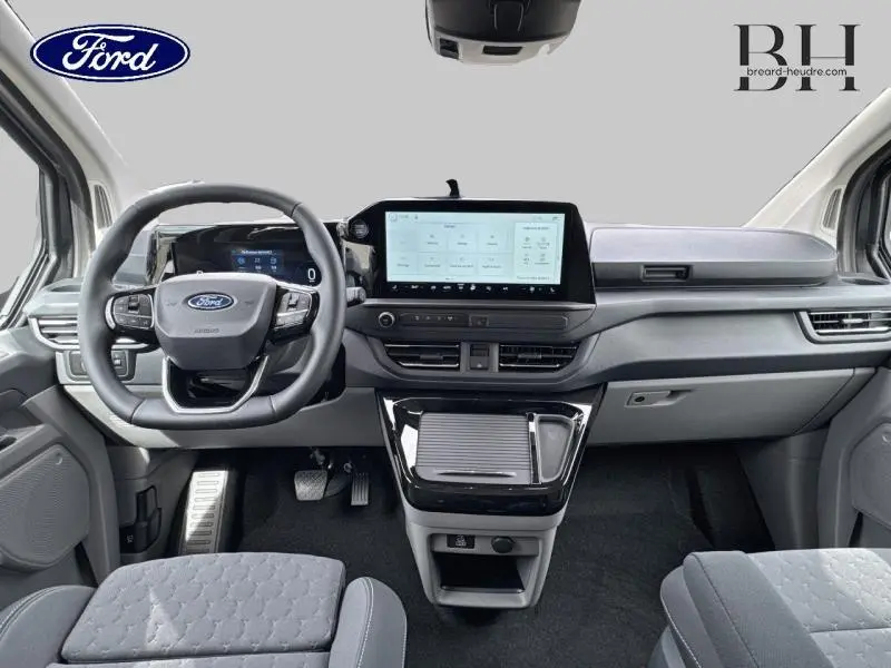 Vue intérieure avant du Ford Transit Custom Fourgon 2026, tableau de bord moderne avec écran tactile central et volant multifonctions.
