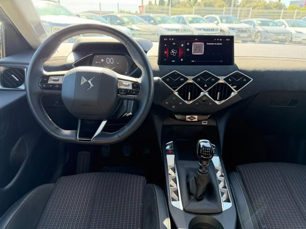 Vue intérieure avant du DS3 2024 gris, mettant en valeur le volant compact et la boîte manuelle au design moderne.