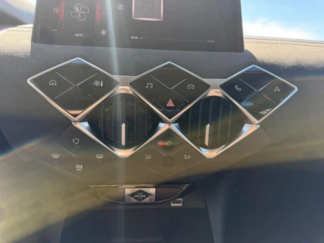 Vue rapprochée de la console centrale du DS3 2024 gris, avec commandes tactiles en losange et aérateurs ronds.