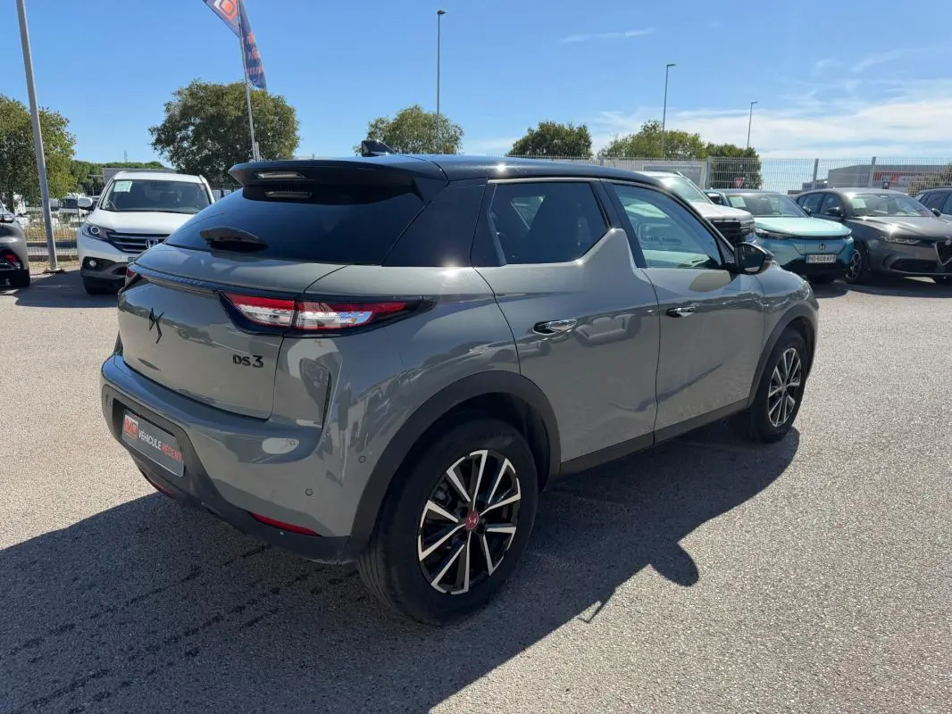 Vue 3/4 arrière droite d'une DS3 100 BVM6 Performance Line gris 2024 avec toit noir et jantes alliage distinctives.