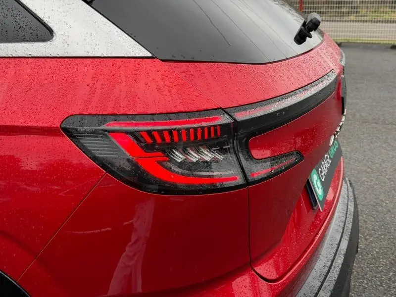 Gros plan sur le feu arrière droit rouge flamme du Renault Austral 2025, version hybride, sous la pluie.