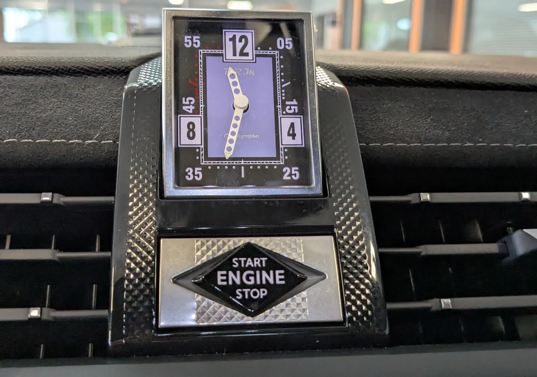 Gros plan sur l'horloge analogique et le bouton start/stop du tableau de bord du DS7 gris laqué, version Pallas 2025.